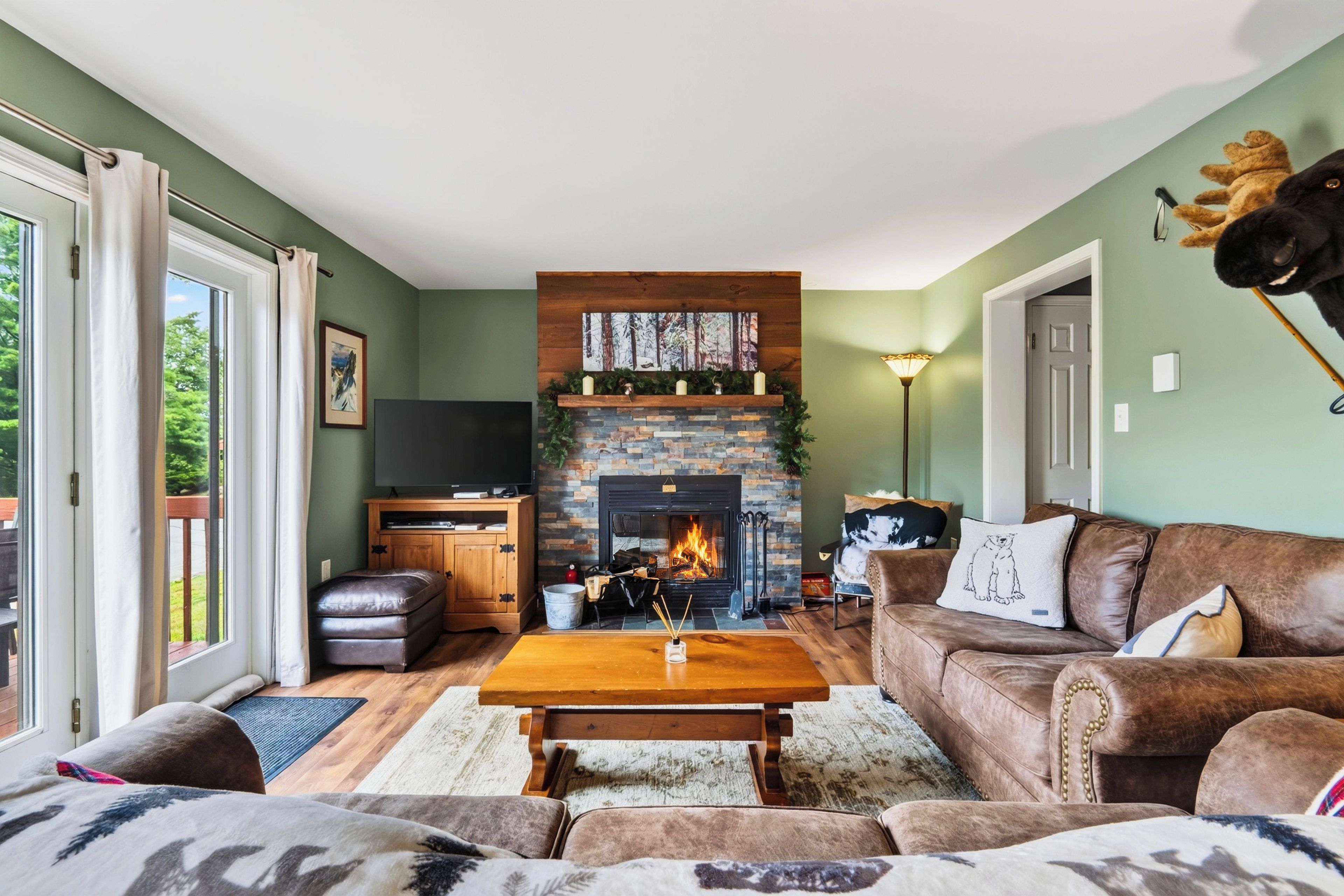A living room with a fireplace, leather furniture, and a television.