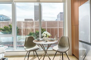 Eine moderne Küche mit großem Fenster, zwei Stühlen, einem Tisch und einem Kühlschrank.