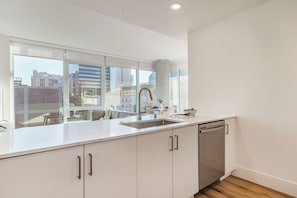 Eine moderne Küche mit großem Fenster, Spüle aus Edelstahl und Geschirrspüler.