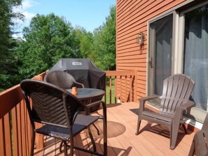 Een terras met buitenmeubilair, een barbecue en een schuifdeur.