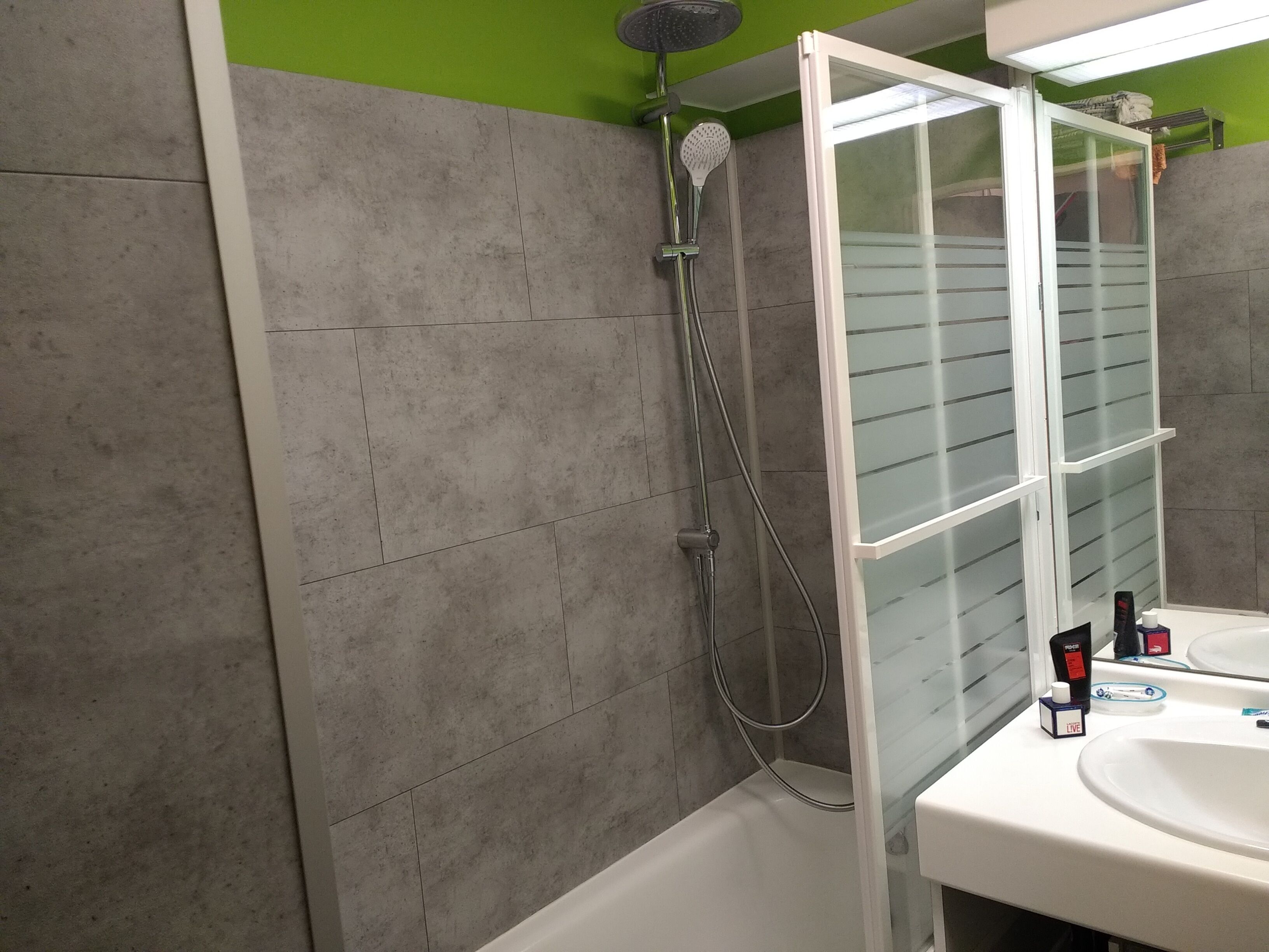 A bathroom with a shower, a sink, and a mirror.