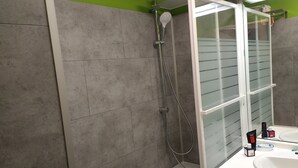 Ein Badezimmer mit Dusche, Waschbecken und Spiegel.