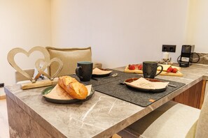 En frukostuppsättning med bröd, kaffe och frukt på en bänkskiva av marmor.