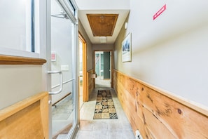 A hallway with a wooden floor, a glass door, a 'No Smoking' sign, and a framed picture on the wall.