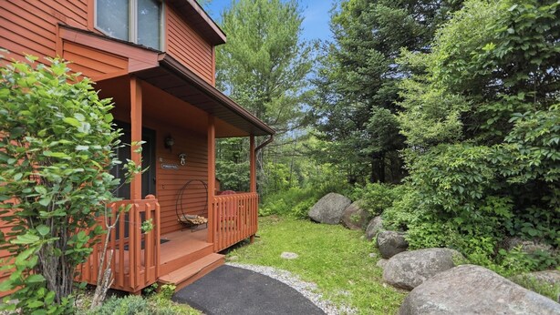 Eine Holzhütte mit Veranda, umgeben von Grünpflanzen und Felsen.