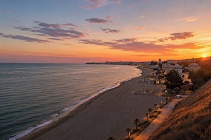 A coastal cityscape at sunset with a beach, buildings, and a clear sky. - Duplex penthouse with pool, parking and magnificent sea and mountain views. (Fuengirola)