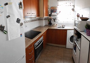 A kitchen with wooden cabinets, a black stove, a washing machine, and a sink. - Duplex penthouse with pool, parking and magnificent sea and mountain views. (Fuengirola)