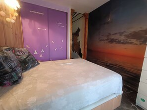 Une chambre à coucher avec un lit, une armoire violette et une fresque représentant un coucher de soleil.