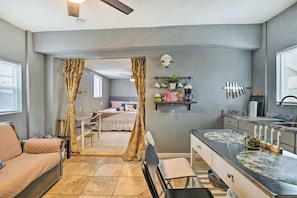 Eine moderne Küche mit Marmorarbeitsplatte, ein Essbereich mit Tisch und Stühlen sowie ein Schlafzimmer mit Bett und Vorhängen.