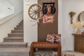 A staircase leading to a room with a neon sign, a wooden wheel, and a bench with patterned cushions. - Pool + Putting Green + Game Room | Coachella Fest | La Casita Retreat Coachella (Coachella)