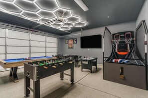 Un garage con tavolo da biliardo, tavolo da calcio e canestro da basket.