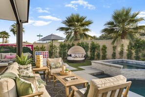 A patio with outdoor furniture, a hot tub, and a palm tree. - Pool + Putting Green + Game Room | Coachella Fest | La Casita Retreat Coachella (Coachella)