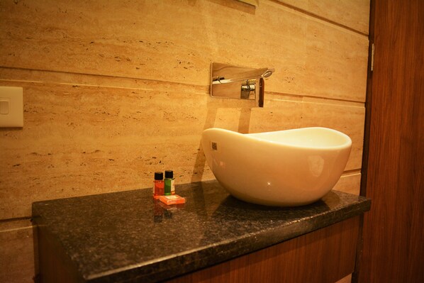 A bathroom with a white sink, a mirror, and a soap dispenser on the countertop. - Hotel Regal (Amritsar)