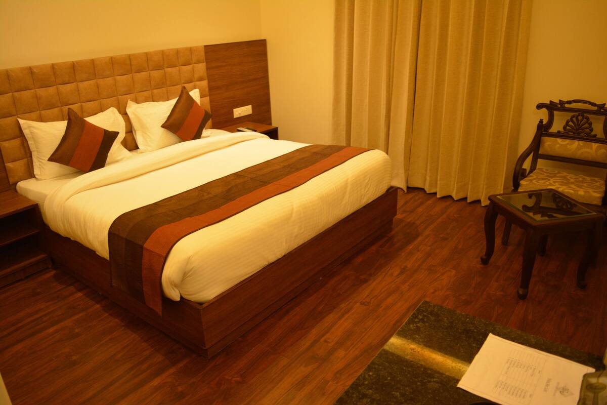 Una habitación de hotel con una cama grande, cabecera de madera y una mesita de noche.