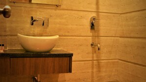 A bathroom with a wooden floor, a white sink, and a mirror. - Hotel Regal (Amritsar)