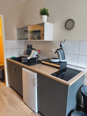 Et moderne køkken med opvaskemaskine, kaffemaskine og elkedel på bordpladen.
