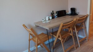 A wooden dining table with four chairs, a coffee maker, and various kitchen items on the table. - Lovely 2-bedroom apartment in Saint-Didier-en-Velay perfect for relaxing (Saint-Didier-en-Velay)