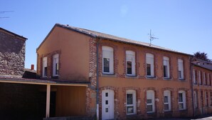 A two-story building with a garage, multiple windows, and a brick facade. - Lovely 2-bedroom apartment in Saint-Didier-en-Velay perfect for relaxing (Saint-Didier-en-Velay)