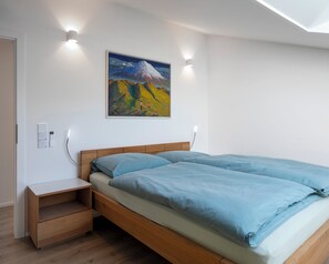 Une chambre à coucher comprenant un lit, des tables de chevet, un tableau et des luminaires fixés au mur.