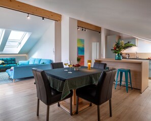 Ein zeitgemäßer Wohnraum mit Esstisch, Stühlen, einer Couch, einer Küchenzeile und einem Oberlicht.