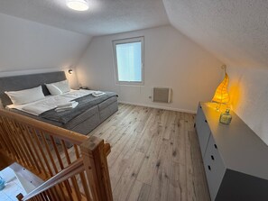 Een slaapkamer met een bed, een raam, een heater en een nachtkastje met lamp.