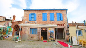 Un edificio de ladrillo con contraventanas azules, una fachada comercial y una calle adoquinada.