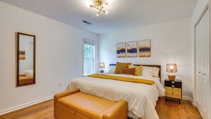 Una camera da letto con un letto, comodini, una panca, un lampadario a soffitto e opere d'arte alle pareti.