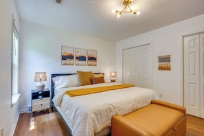 Un dormitorio con cama, mesitas de noche, un banco, una lámpara de pared y una lámpara del techo.