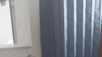Un baño con cortina de ducha, lavamanos, espejo e inodoro.