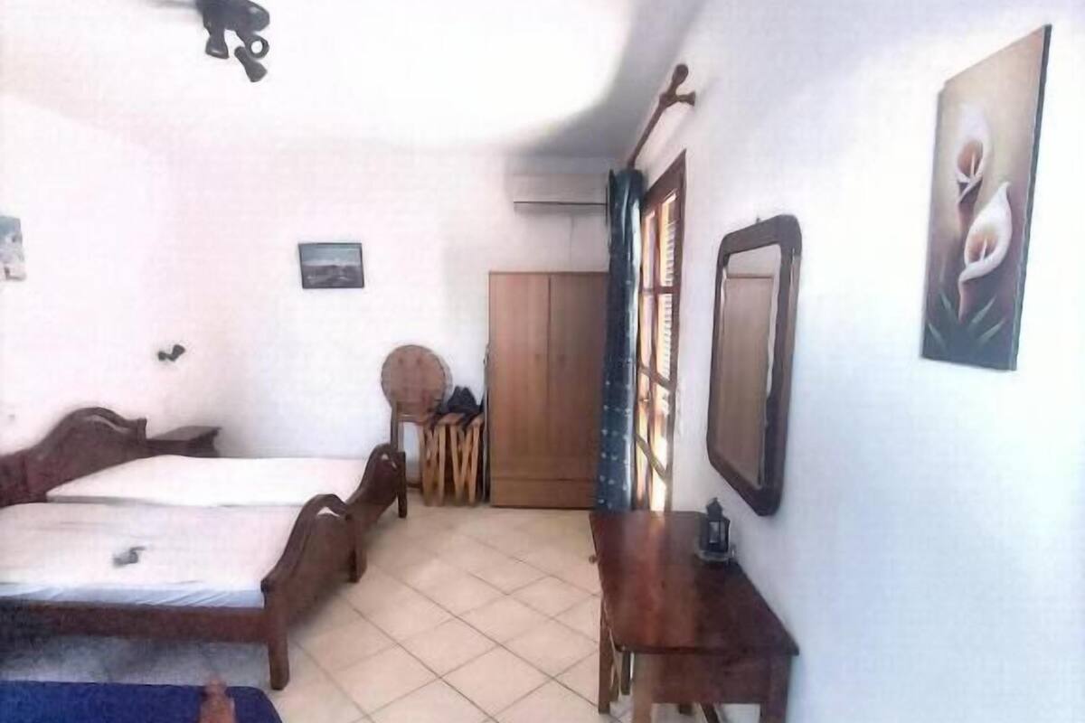 A room with two beds, a desk, a chair, a wardrobe, and a television.