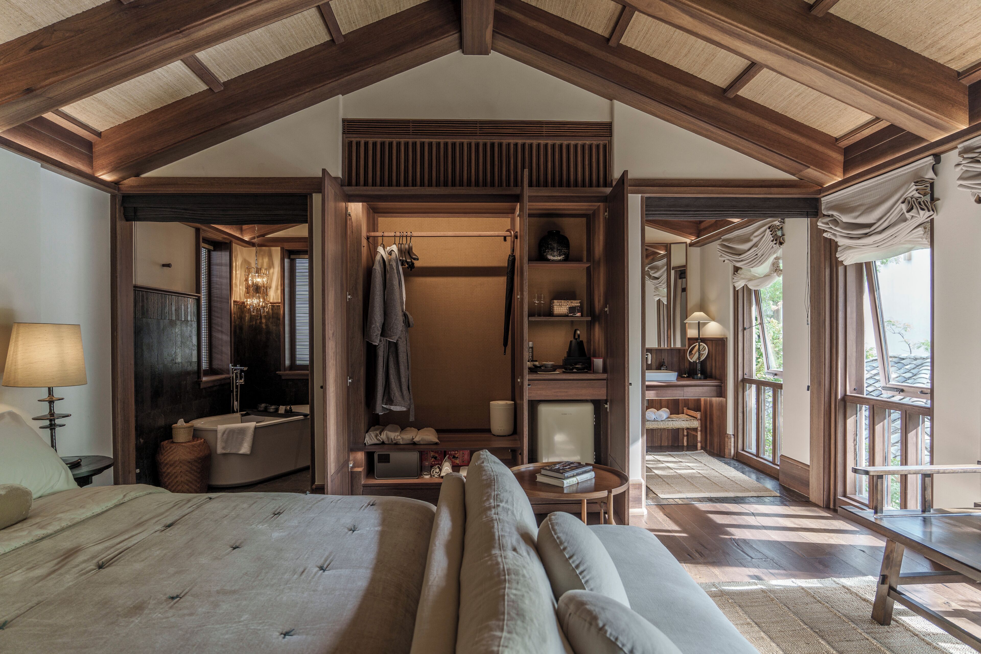 A spacious bedroom with a large bed, a walk-in closet, and a view of the outdoors.