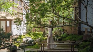 Un jardín japonés tradicional con un puente de madera, faroles de piedra y un estanque.