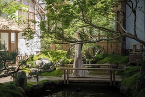 A traditional Japanese garden with a wooden bridge, stone lanterns, and a pond. - MistyHues DawnGreen (Lijiang)