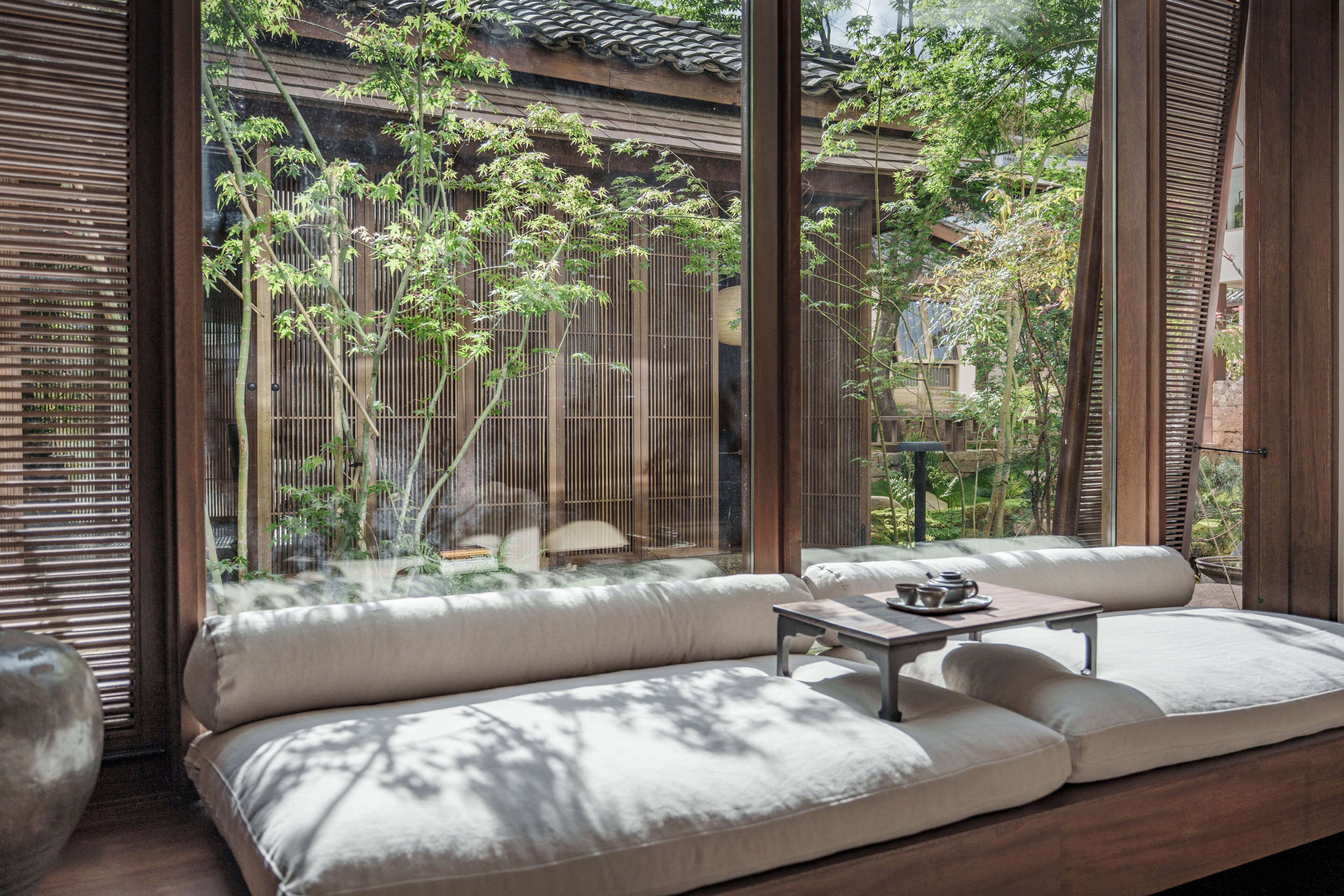 A traditional Japanese-style room with tatami flooring, a low wooden table, and a cushioned seating area.