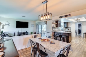A modern kitchen with a central island, a dining area with a patterned tablecloth, and a 'Welcome' sign on the wall. - Game Room, Pool & Lake Fun at 'Indian Land Oasis' (Lake Havasu City)