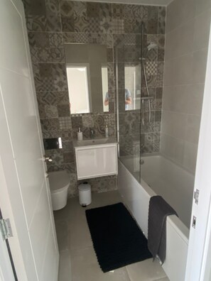 A bathroom with a shower, toilet, and sink.