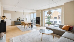 Un vaste espace de vie comprenant une table à manger, un canapé et de grandes fenêtres offrant une vue sur la ville.