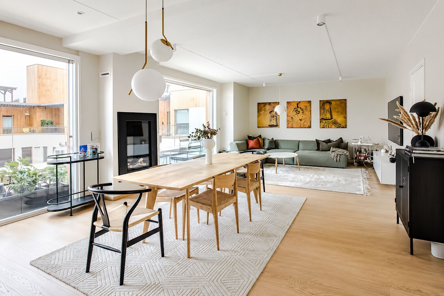 Un salon moderne avec un coin repas, de grandes fenêtres et des œuvres d’art accrochées aux murs.