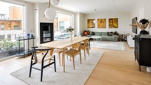 Un salon moderne avec un coin repas, de grandes fenêtres et des œuvres d’art accrochées aux murs.