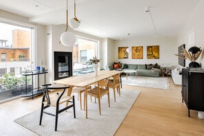 A modern living room with a dining area, large windows, and artwork on the walls. - Luxury Penthouse | Sea Views & Terraces | 3 Bed, 2 Bath | Walk to Opera & MUNCH (Oslo)