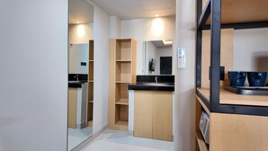 A modern kitchen with a black countertop, wooden cabinets, and a built-in oven. - Casa Mysa Hotel Kuta (Kuta)