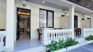 Entrada de un hotel con fachada blanca, un balcón con balaustrada y una puerta marcada con el número 127.