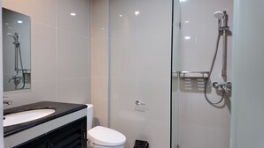 A modern bathroom with a glass shower enclosure, a white toilet, and a black sink. - Casa Mysa Hotel Kuta (Kuta)