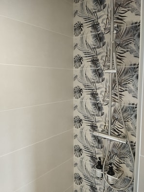 A bathroom with a shower, a tiled wall, and a showerhead. - Chambre D'hôte La Canissa Carrada Indigo (Chaspuzac)