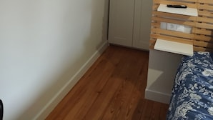 Un dormitorio con cama, armario, luz empotrada y toma de corriente.