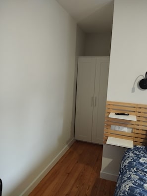A bedroom with a bed, a wardrobe, a wall-mounted light, and a power outlet. - Chambre D'hôte La Canissa Carrada Indigo (Chaspuzac)