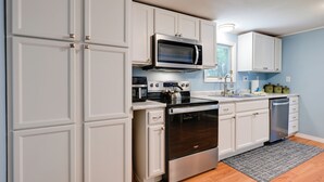 A modern kitchen with white cabinetry, stainless steel appliances, and a wooden floor. - Waterfront Days, Fireside Nights! Lake Helen Haven (Rosholt)