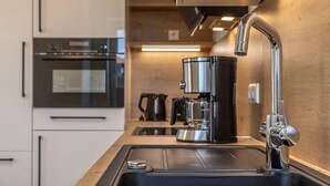 Una cocina moderna con electrodomésticos de acero inoxidable, una cafetera y un lavamanos.
