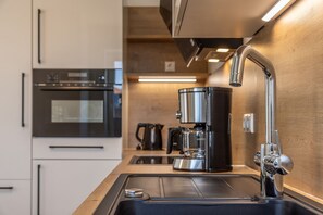 Eine moderne Küche mit Edelstahlgeräten, einer Kaffeemaschine und einem Spülbecken.