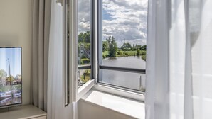 Una ventana con vistas a un lago, un muelle con barcos y una zona residencial.